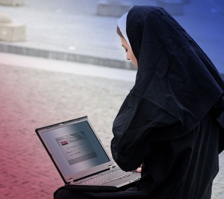 Eine als Nonne gekleidete Person hält auf Ihrem Schoß einen Laptop. Geöffnet ist die Zugangsoberfläche zum Simba Direkt Portal.