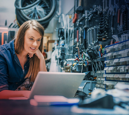 Eine Frau arbeitet in einer Werkstatt an einem aufgeklappten Laptop